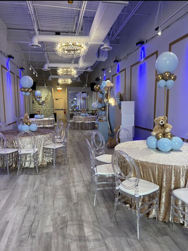 Boy baby shower tables with gold linens, blue balloons and teddy bear centerpieces
