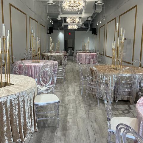Mesas con manteles de terciopelo champán y rosa palo con candelabros dorados altos bajo lámparas de cristal