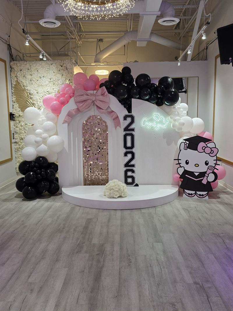 Fondo de graduación con letrero 2026, una Hello Kitty graduada con birrete y toga, globos rosas, blancos y negros