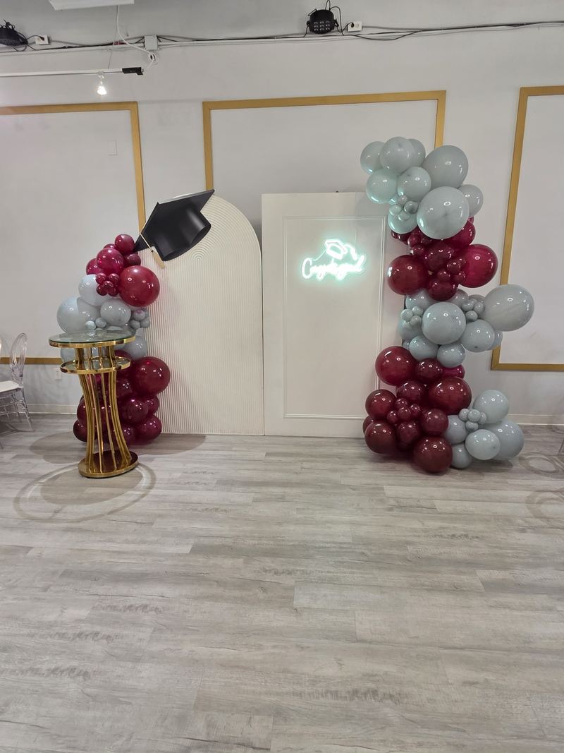 Fondo de graduación con birrete, letrero de neón “Congrats” y globos color vino y grises