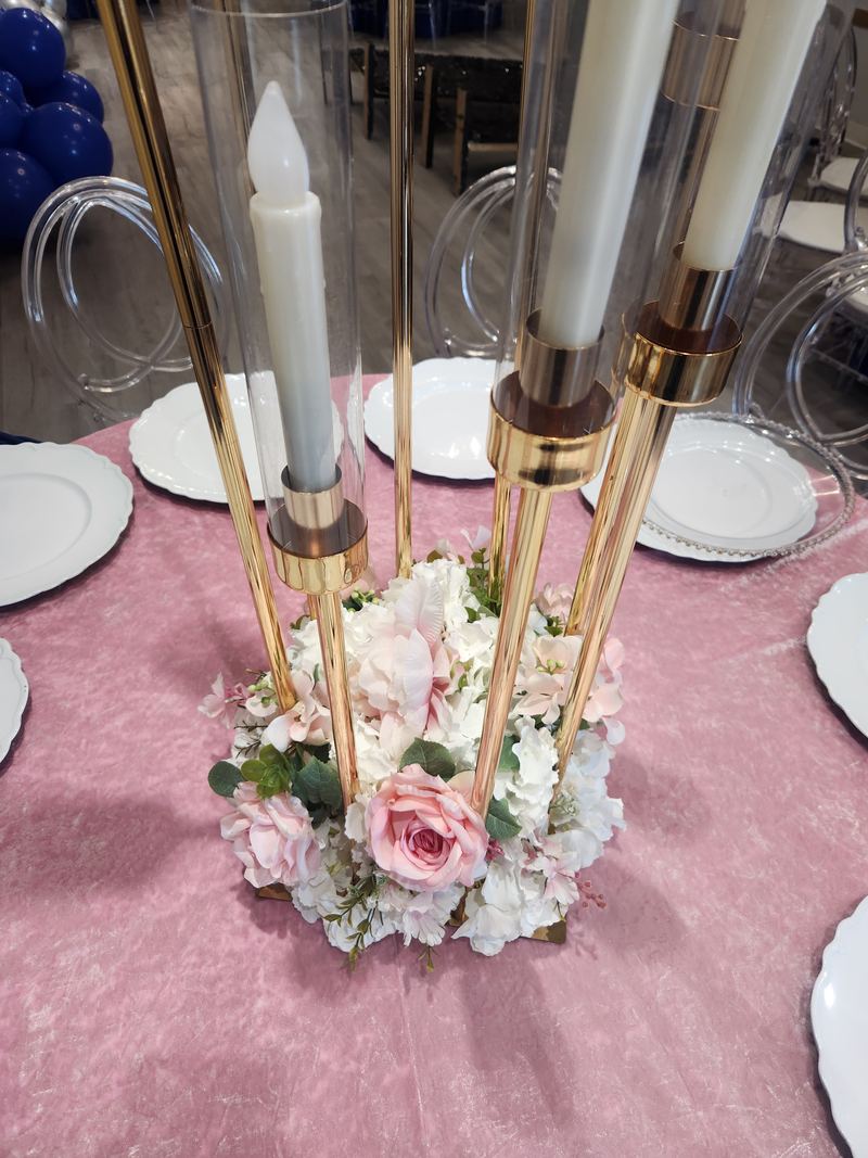 Mesa con mantel rosa, candelabro dorado con velas blancas y flores rosas y blancas