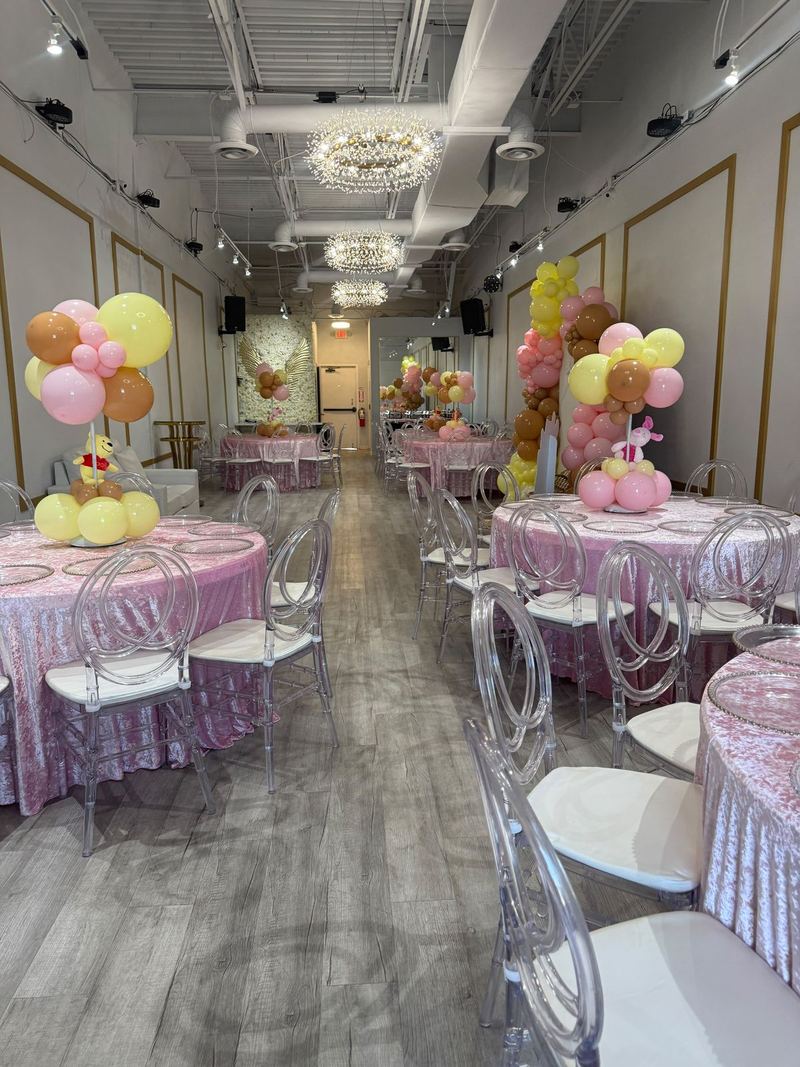 Mesas con manteles rosas de lentejuelas, arreglos de globos y sillas transparentes