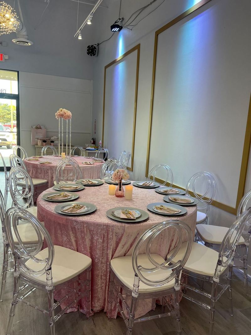 Mesa con mantel rosa de lentejuelas y sillas transparentes
