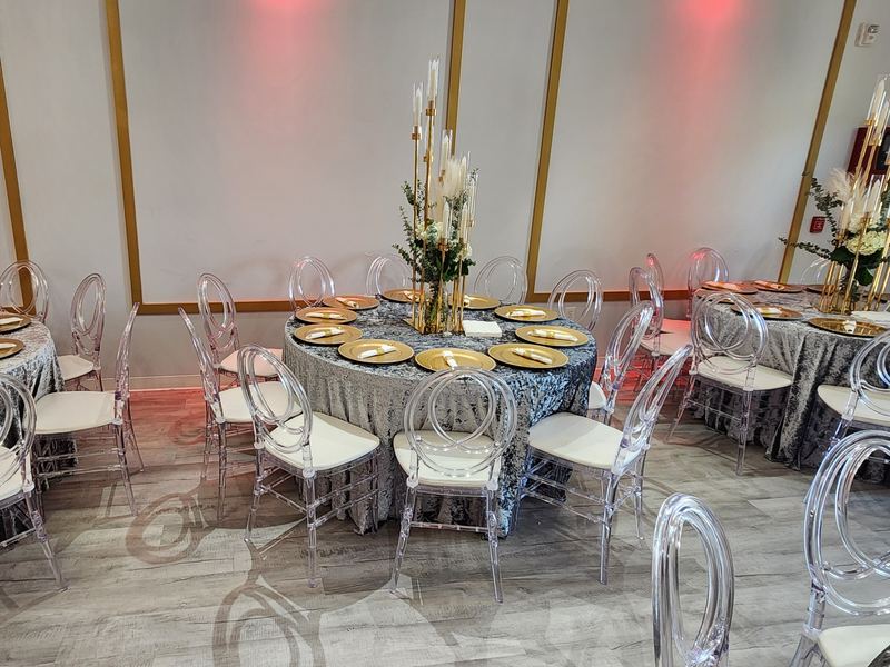 A round table at Moon Angel Event Venue with a tall gold candelabra centerpiece, white flowers and gold charger plates