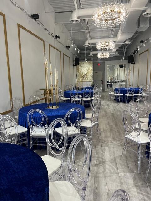 Mesas redondas con manteles azul rey, sillas transparentes y candelabros dorados