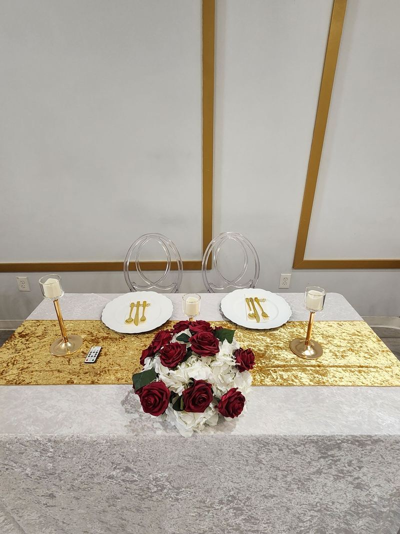 Sweetheart table with red roses, gold runner and two clear chairs