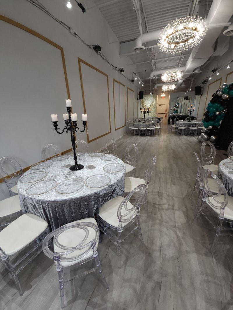White tables with candelabra centerpieces under the chandeliers