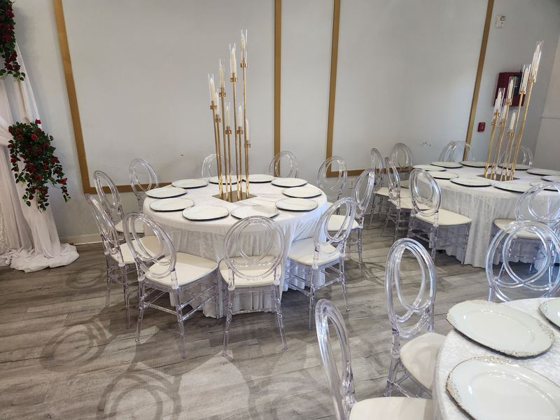 Round tables with white linens and tall gold candelabras under crystal chandeliers
